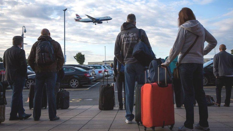 Passengers wait for a shuttle bus at Heathrow