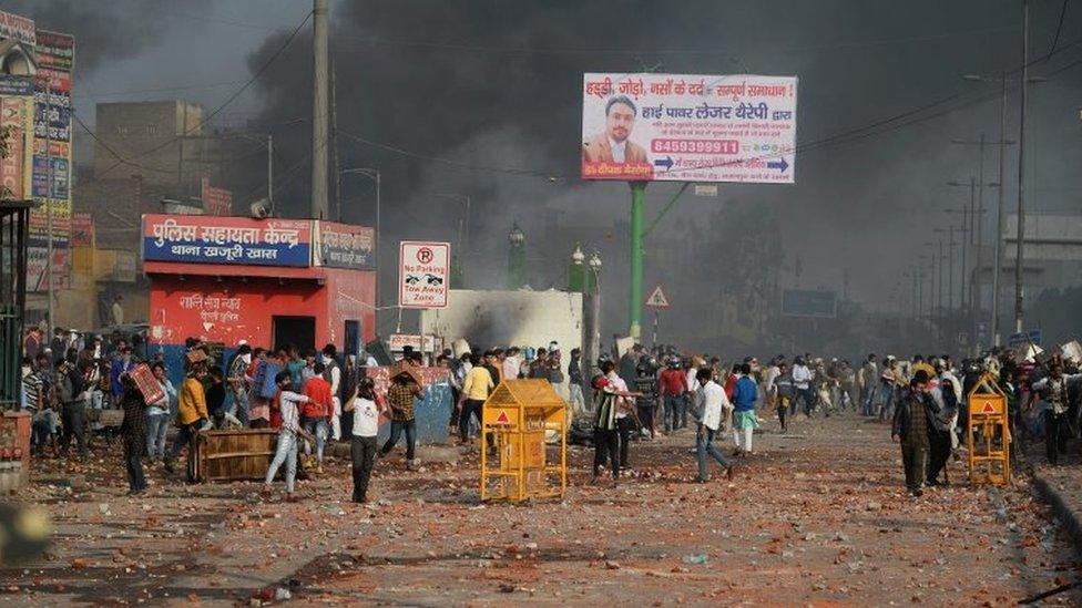 Demonstrators gather along a road scattered with stones following clashes between supporters and opponents of a new citizenship law, at Bhajanpura area of New Delhi on February 24, 2020