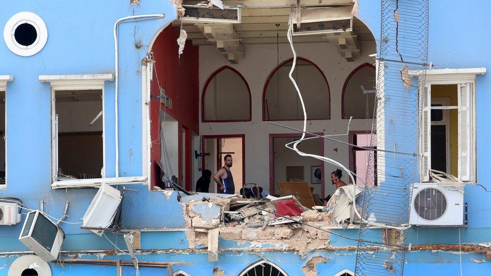 Men inspect a damaged building near Beirut's port area (6 August 2020)