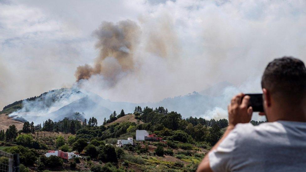 A man takes a photo on his smartphone during wildfires in Gran Canaria