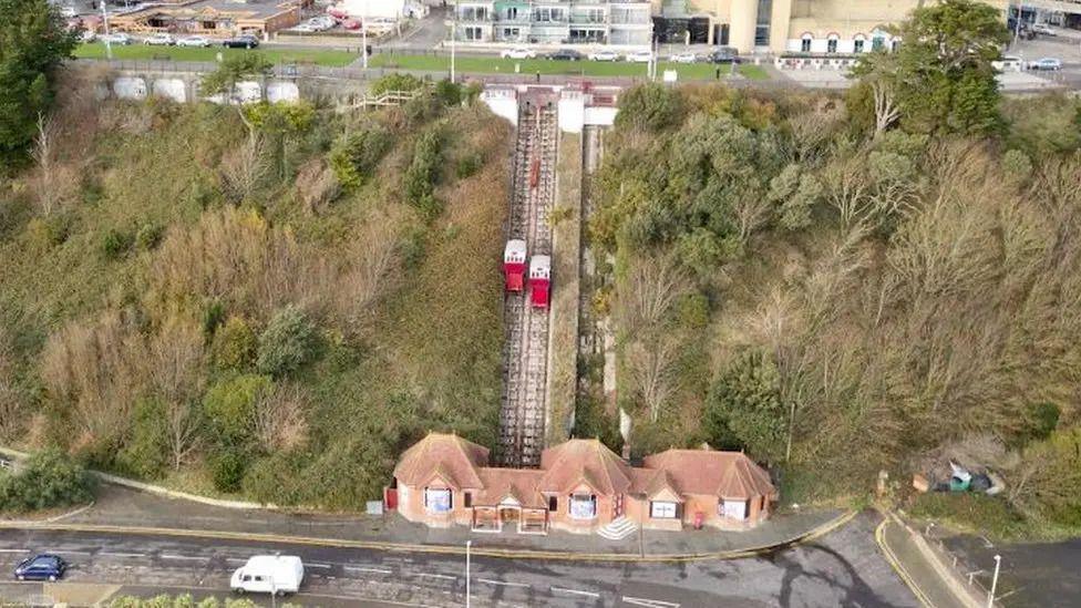 A funicular lift on a cliffside covered in trees