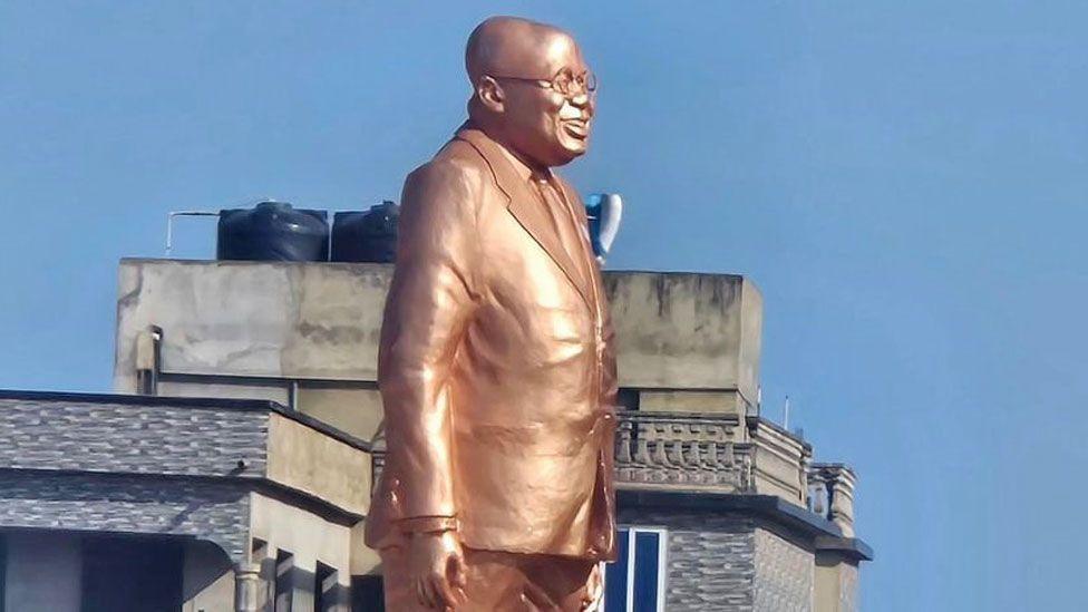 The statue of Nana Akufo-Addo, which is bronze in colour. He is in profile, depicted wearing a suit, his glasses and is smiling. It is outside Effia-Nkwanta Regional Hospital in Sekondi, Ghana - November 2024