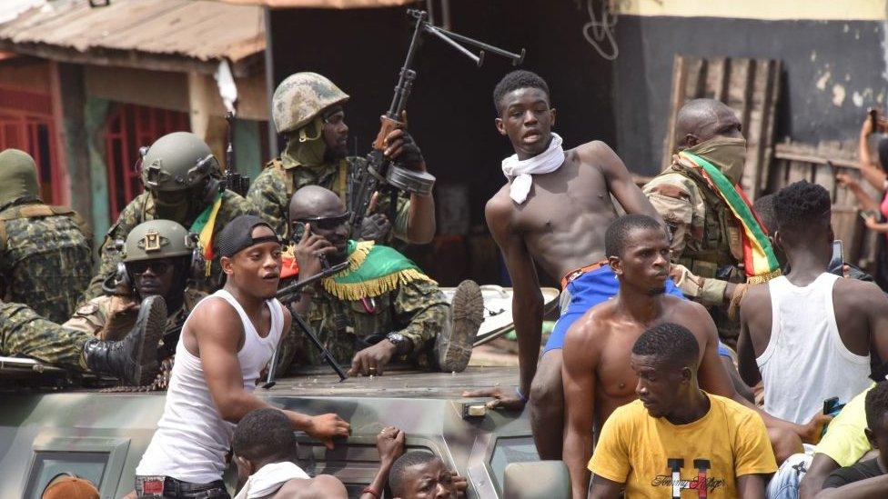 People celebrate in the streets with members of Guinea's armed forces after the arrest of Guinea's president, Alpha Conde