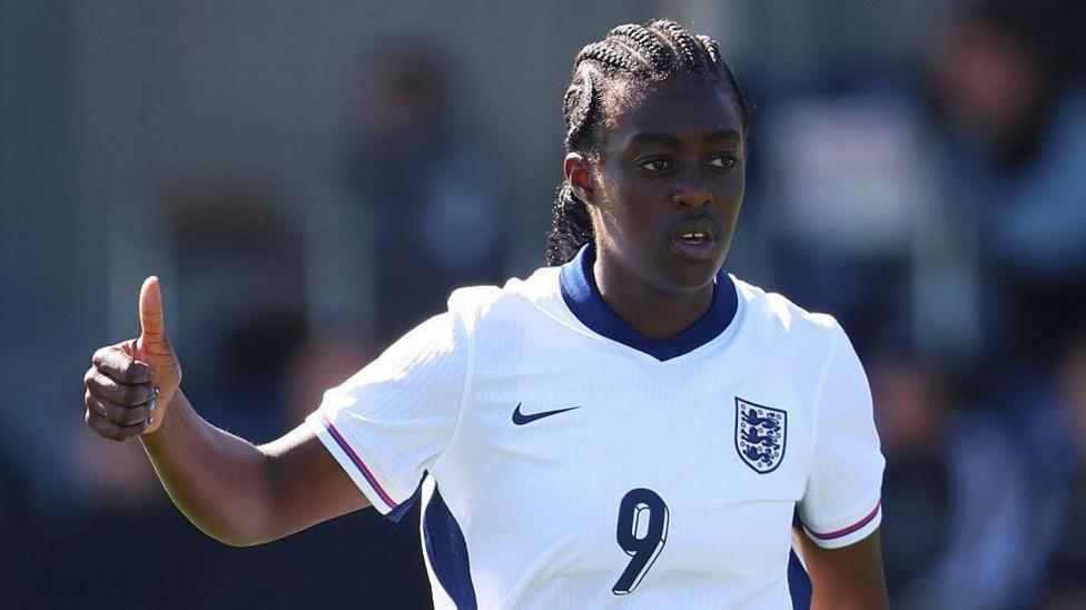 England player Michelle Agyemang, wearing the team kit, gives a thumbs-up gesture