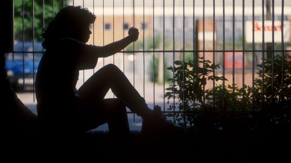 A young girl in silhouette next to some railings