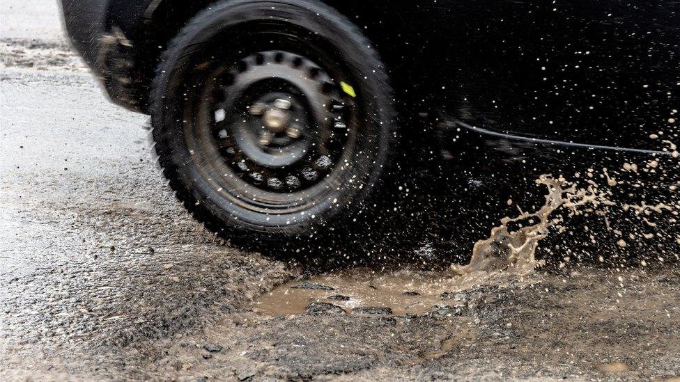 Car tyre driving through wet pothole