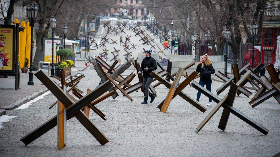 People walk among anti-tank barriers placed to protect historic landmarks