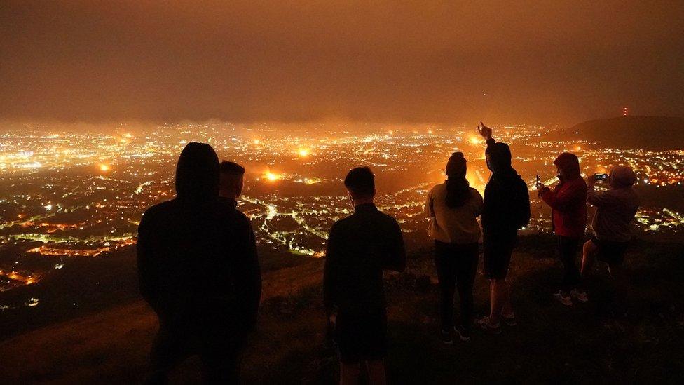 People watching bonfires from a viewpoint in the Belfast hills