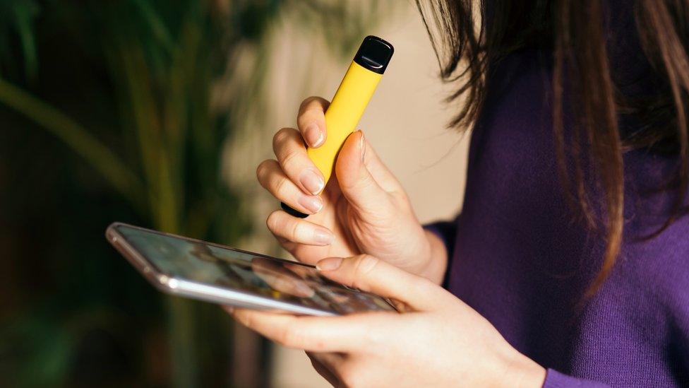 A young person using a disposable vape