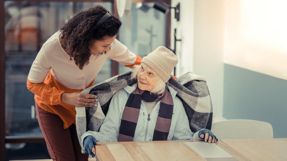 Woman covering an elderly woman with a blanket