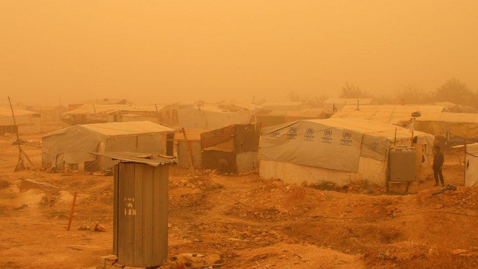 Syrians talk in front of a tent during a sandstorm on September 7, 2015 at a refugee camp on the outskirts of the eastern Lebanese city of Baalbek