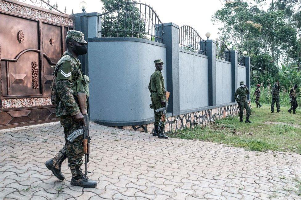 Soldiers stand next to a wall of the neighbours of presidential candidate Robert Kyagulanyi, also known as Bobi Wine, in Magere, Uganda, on January 15, 2021