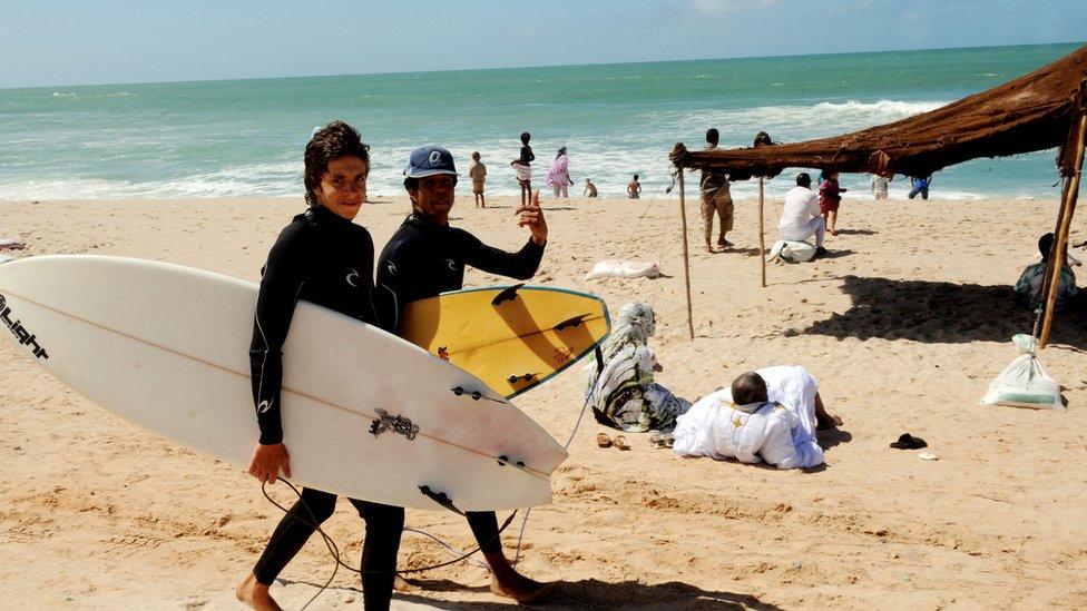 Two surfers walking on a beach in Dakhla, Western Sahara.