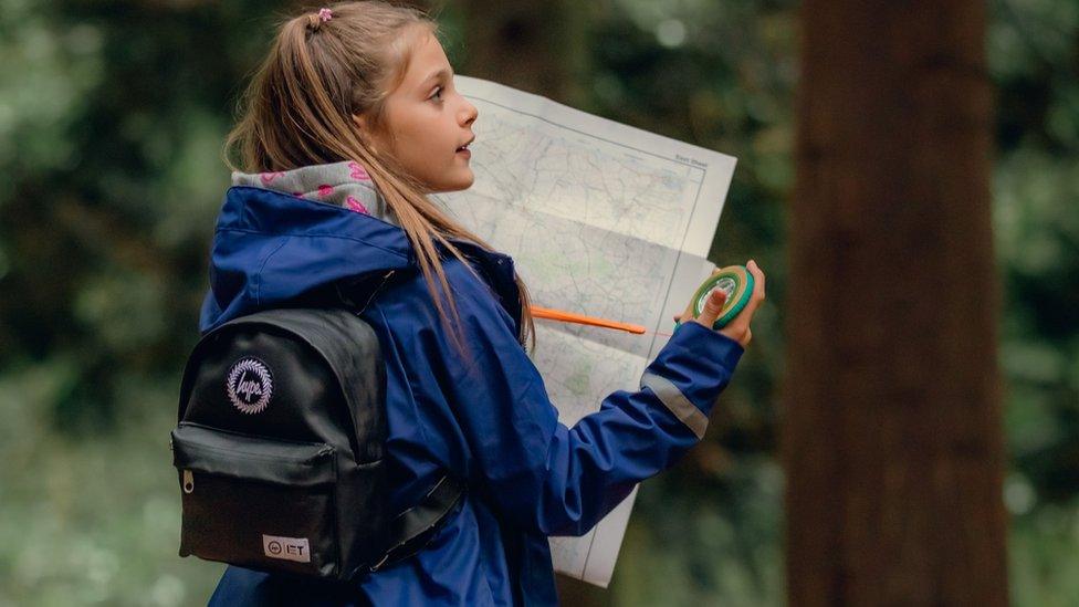 Girl with backpack holding map in forest