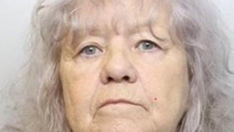 A police mugshot of Christina Pomfret, who has shoulder length grey hair and blue eyes