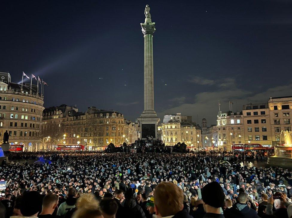 A wideshot of a large group of peopple in Trafalgar Square