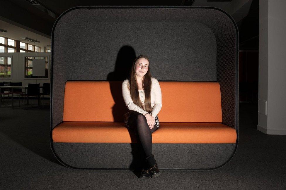 Gracie O'Grady, 18, sitting on an orange and black sofa at Harlow College