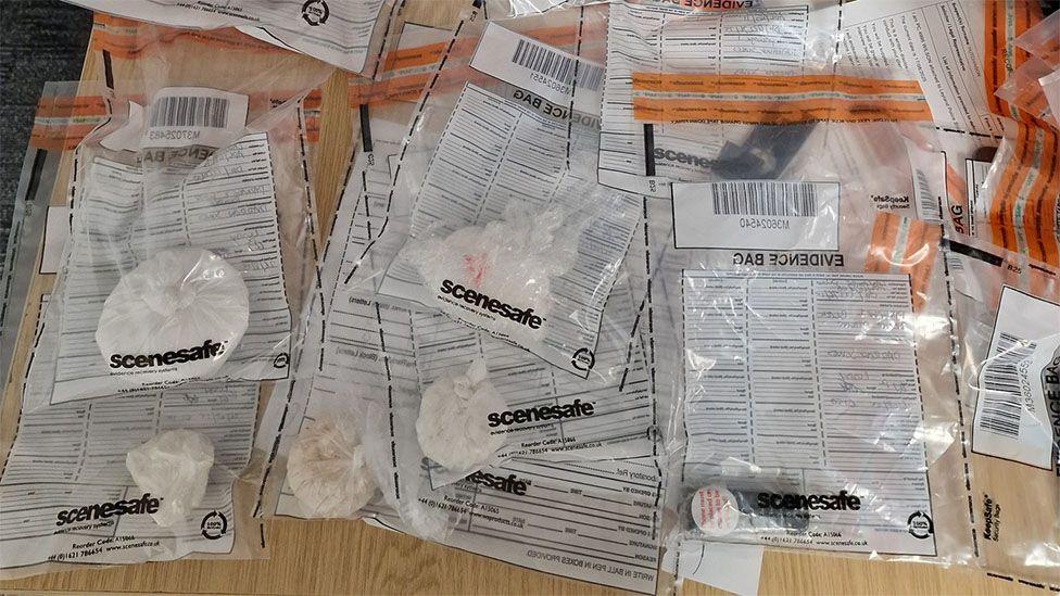Evidence bags scattered on a table with drugs inside