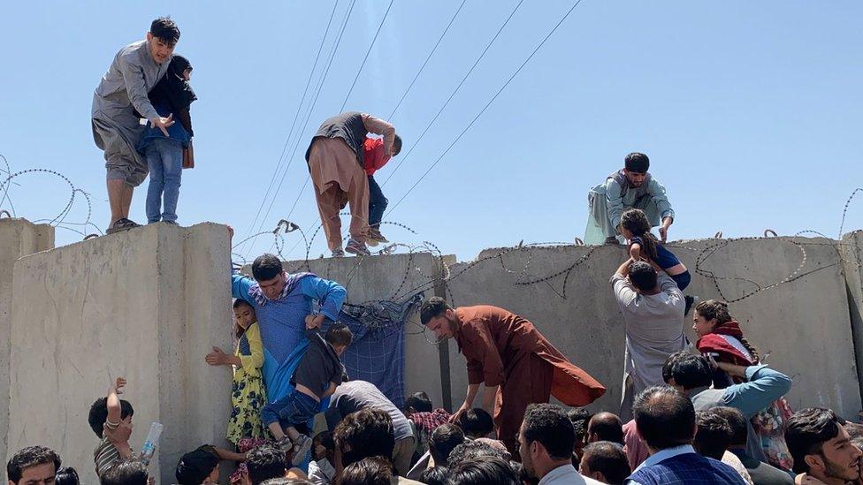 People climb the boundary wall of Hamid Karzai International Airport