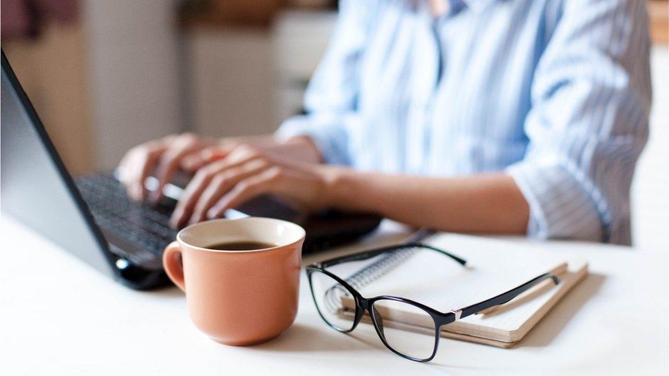 Woman typing on laptop with coffee mug