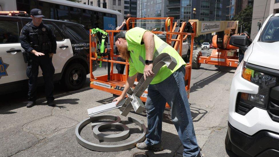 Worker removes letters from the sign and puts them on the ground