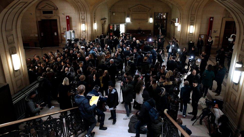 Journalists and victims stand on the opening day of the trial of Jawad Bendaoud