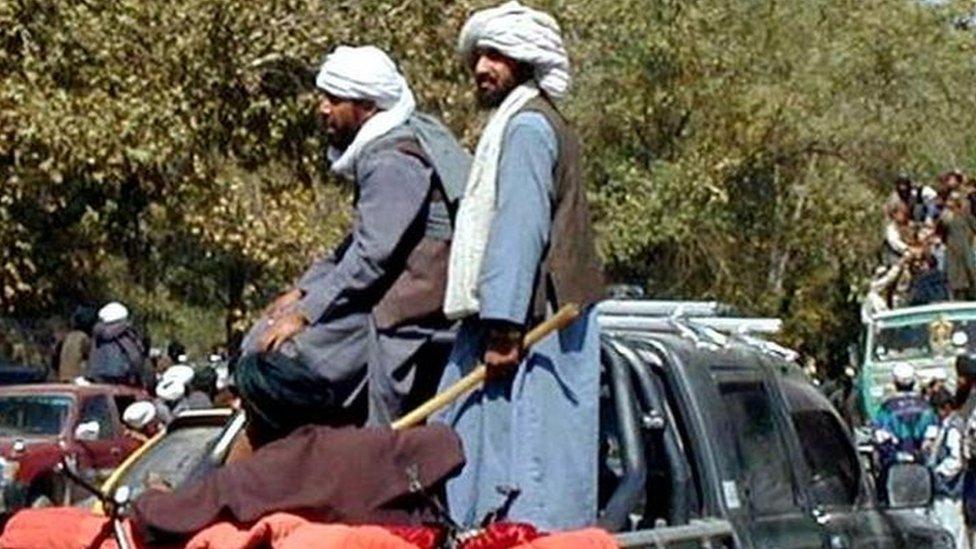 Taliban militia stand in a pick-up truck as demonstrators ride ahead atop a vehicle in Kabul, Afghanistan, Wednesday, Sept. 26, 2001.