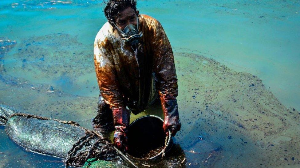 A man scoops leaked oil from the vessel MV Wakashio on 8 June.