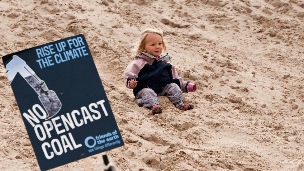 Young child with poster against the coal mine