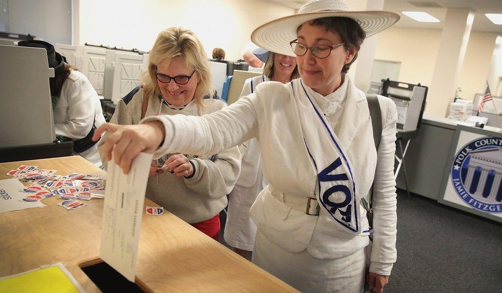 A woman dressed as a suffragette casts her ballot for the midterm elections at the Polk County Election Office on October 8, 2018