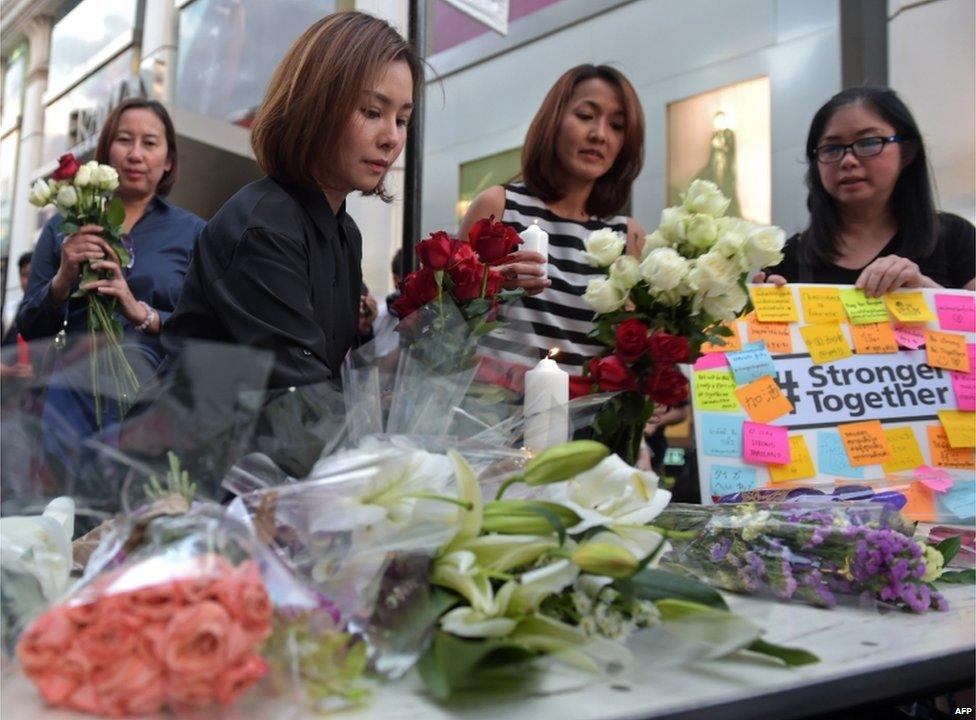 Thai office workers lay flowers for victims killed in a bomb blast outside a religious shrine in Bangkok on 18 August 2015