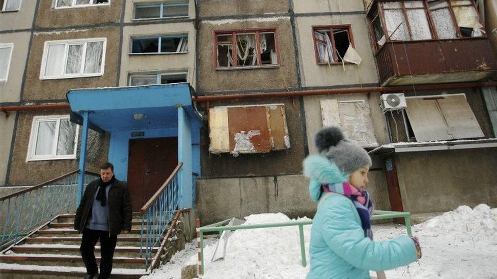 Residents walk past a damaged apartment building in the rebel-held city of Donetsk, eastern Ukraine. Photo: 2 February 2017