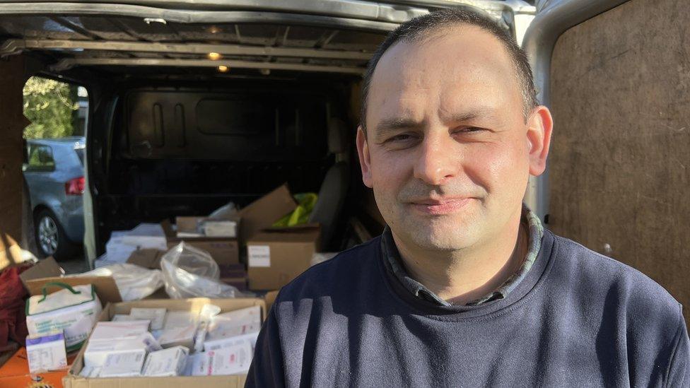 A man smiling in front of a van load of supplies going to Ukraine