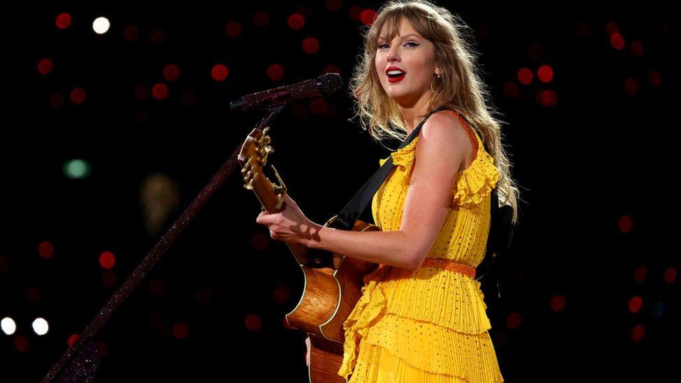 Taylor Swift holding a guitar.