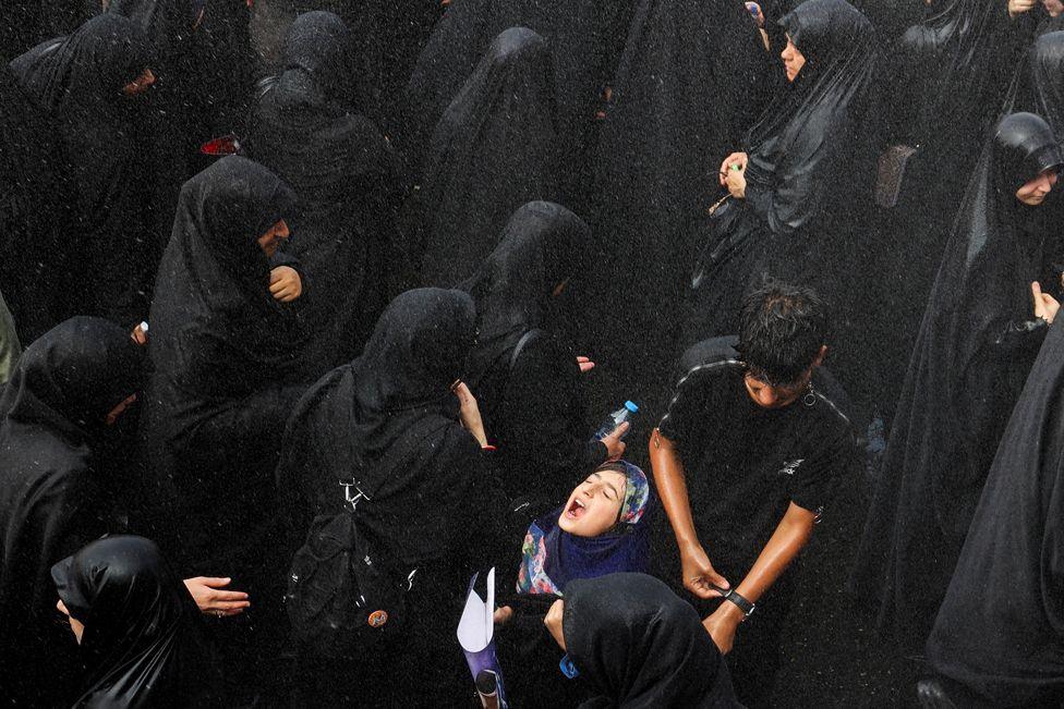 A woman reacts as it rains during the funeral procession of assassinated Hamas chief, Ismail Haniyeh in Tehran, Iran, August 1, 2024. 