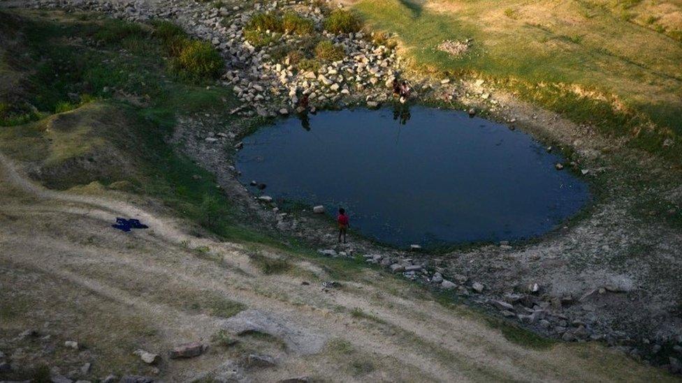 Indian villagers try to catch fish in a pool of the shrunken Mansaita River near Allahabad on May 4, 2016.