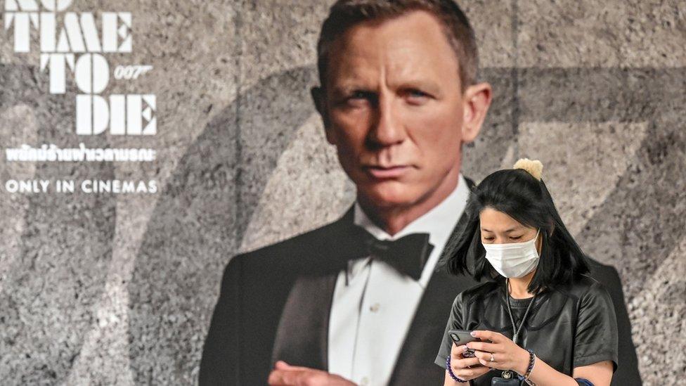 A moviegoer wearing a mask, pictured in front of a James Bond poster