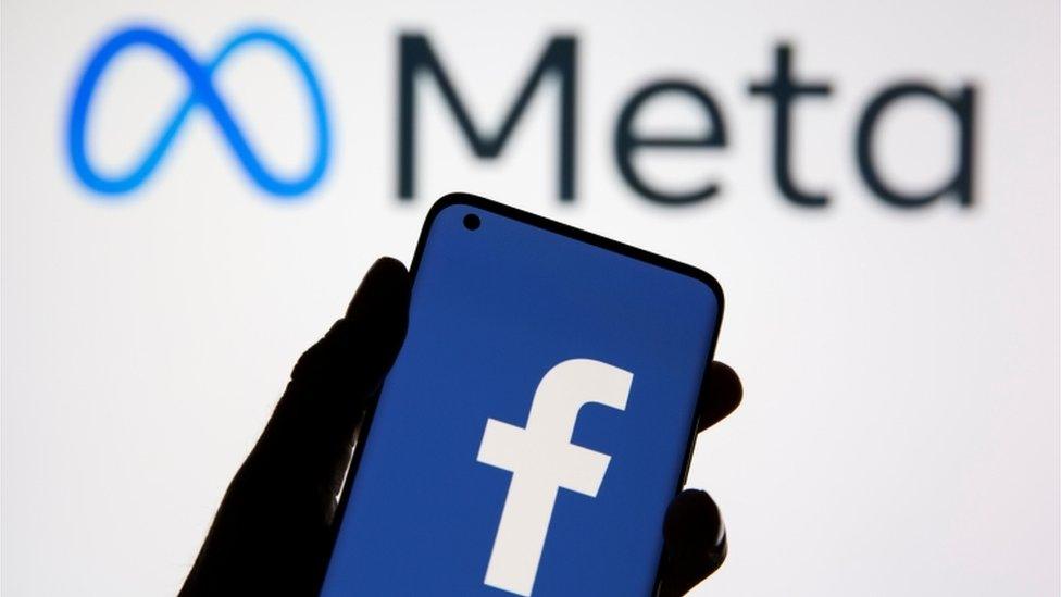 Facebook logo on phone with Meta logo in background