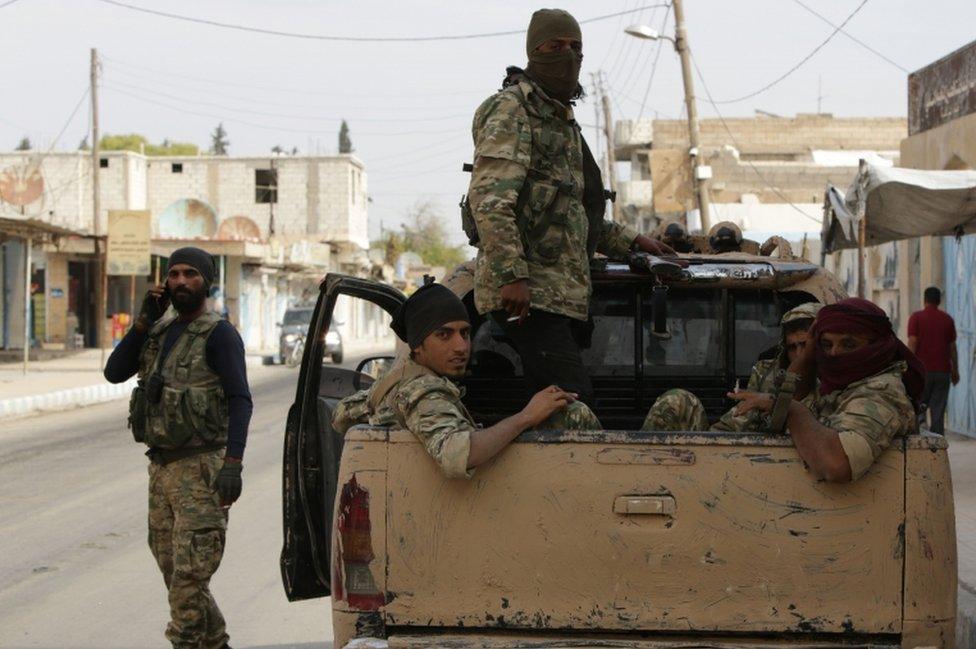 Turkish-backed Syrian fighters sit in the back of a truck in the Syrian border town of Tal Abyad on October 17, 2019