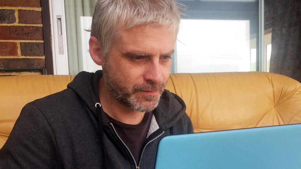 Iain Taylor, who writes fake reviews, sits at his laptop