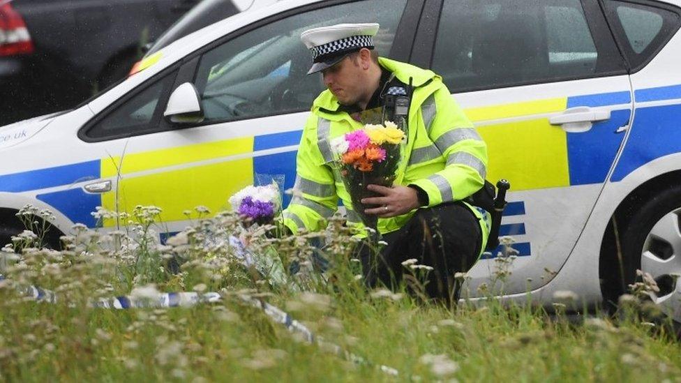 A police officer lays flowers at the scene where PC Andrew Harper was killed