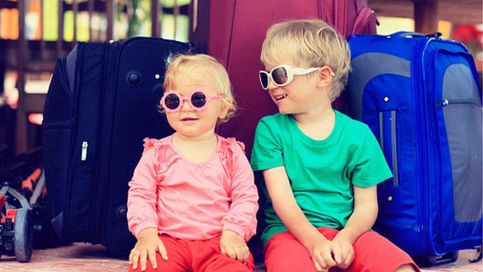 Children sat on suitcases