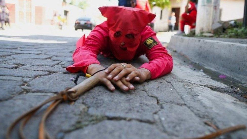 A man dressed as a demon lies on the ground as he participates in a ceremony known as Los Talciguines, as part of religious activities to mark the start of the Holy Week in Texistepeque, El Salvador, April 11, 2022.