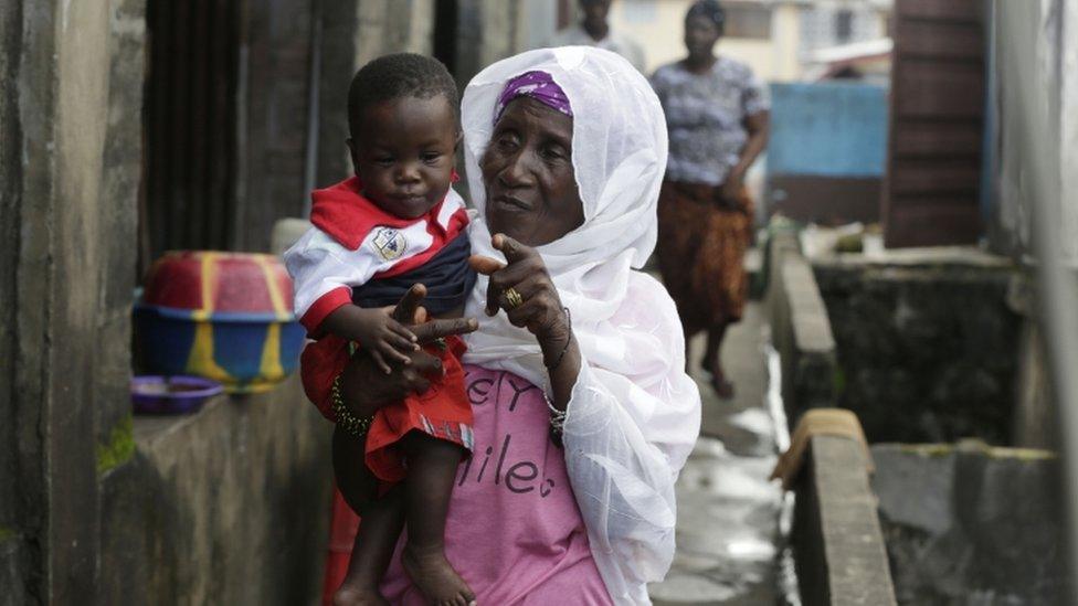 Great-grandmother Marie and adopted great-grandson Donnell Junior outside their apartment in Freetown, Sierra Leone