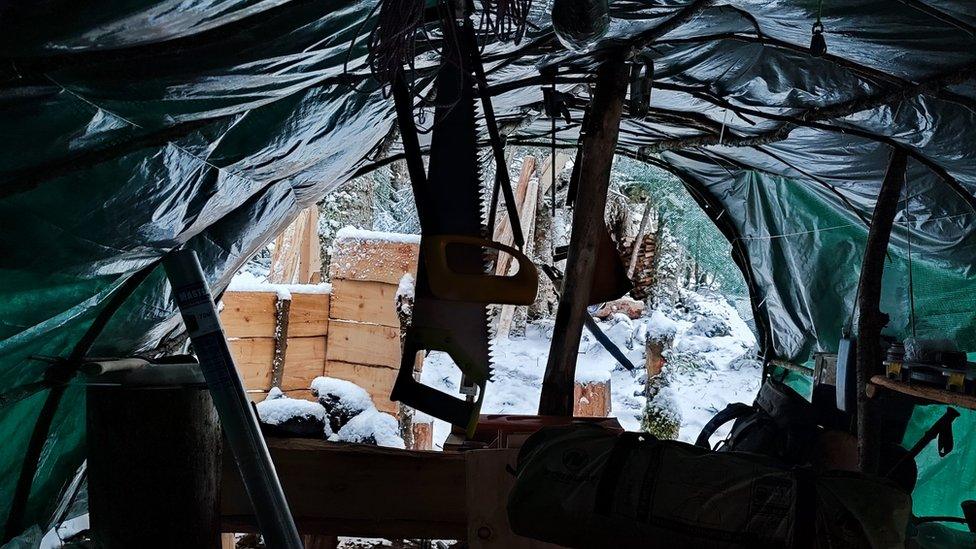 A saw for chopping wood hangs from the roof of a tent