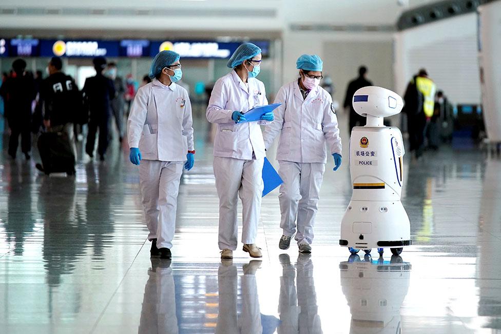 Medical workers walk past a police robot