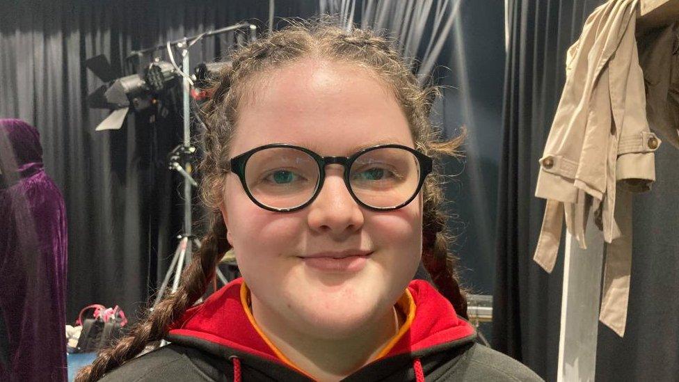 Young woman with long hair in pigtails and glasses, in a rehearsal studio