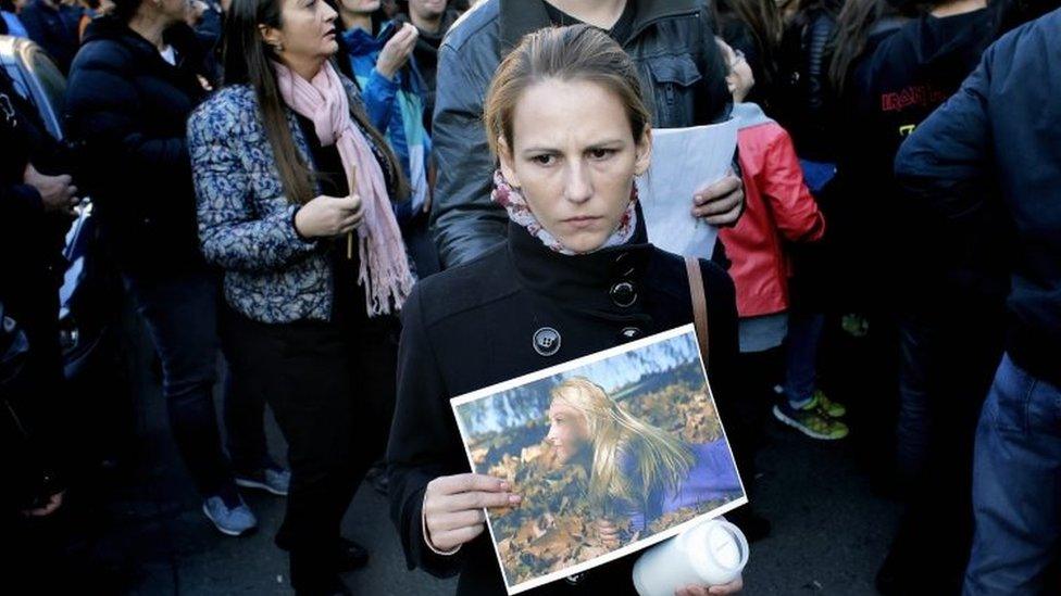 A Romanian woman holds a portrait of her dead close friend, while queuing to pay respect for the club blaze victims at the end of a silent march in front of the fire site (01 November 2015)