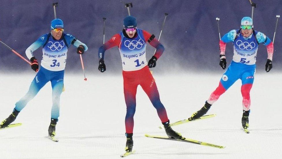 Quentin Fillon Maillet of France, Johannes Thingnes Boe of Norway and Eduard Latypov of the Russian Olympic Committee in action at 2022 Olympics