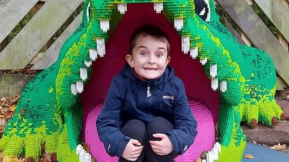 A boys sits in the mouth of a giant Lego crocodile